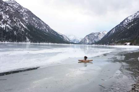 Eine Frau badet in einem zugefroren See. 